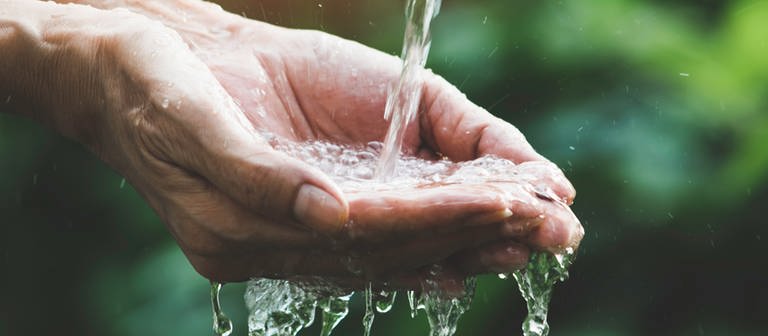 Wasser fließt in eine Hand - Symbolbild zum ARD-Thema #unserWasser: Den Persönlichen Wasserfußabdruck kennen und den Wasserverbrauch pro Person senken, das ist Klimaschutz. (Foto: iStock / Mintr)