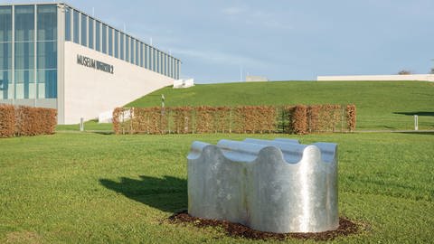 Richard Deacons Plastik "Groundswell", eine organische Form aus Edelstahl, misst 90 x 280 x 172 cm - im Hintergrund ist das Gebäude Museum Würth 2.  (Foto: Schambeck-Schmitt)