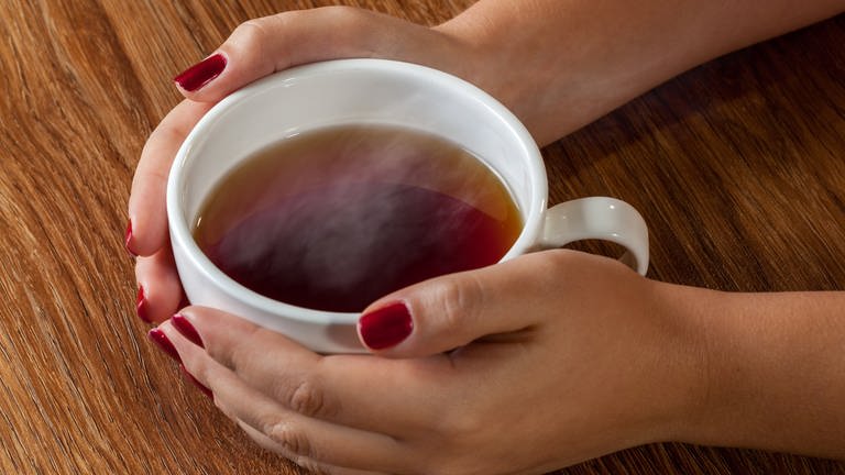 Frau umfasst eine Tasse mit Tee (Foto: Colourbox)