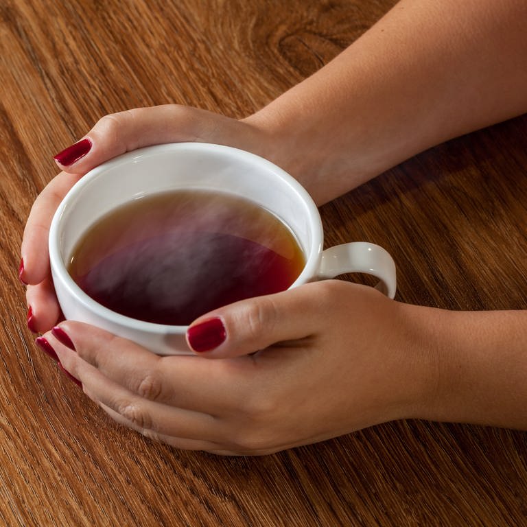 Frau umfasst eine Tasse mit Tee