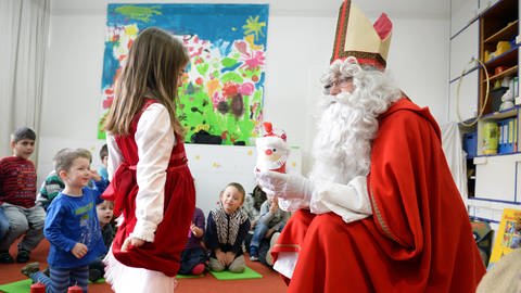 Nikolaus spricht mit einem Mädchen und hat ein Geschenk in der Hand (Foto: dpa Bildfunk, Felix Kästle)