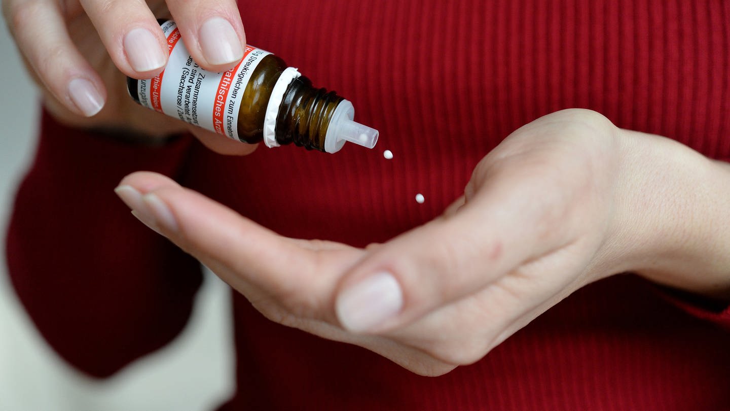Person schüttet sich homöopathische Arzneimittel Globuli aus Fläschchen in offene Handfläche. (Foto: picture-alliance / Reportdienste, Frank May)
