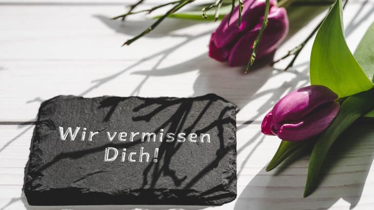 Tulpen mit einer Schieferplatte mit Aufschrift: Wir vermissen Dich