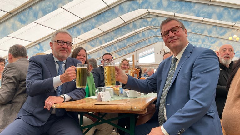 Minister Peter Hauk und OB Peter Kurz (l.) stoßen auf dem Maimarkt mit einem Bier an.