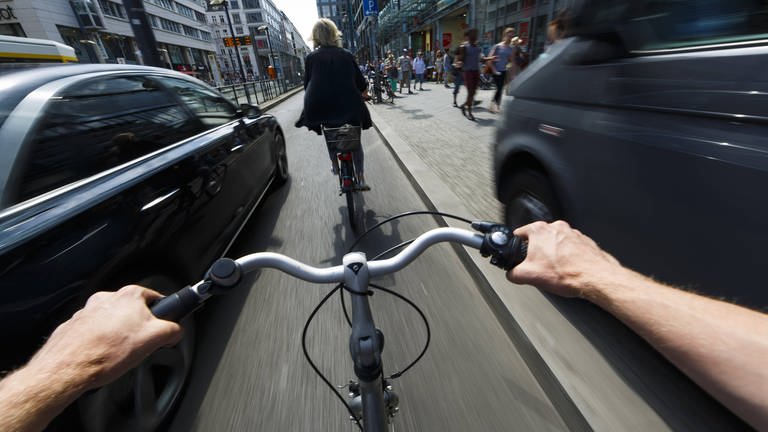 #besserRadfahren: Ein Radfahrer wird im Stadtverkehr von einem nah vorbeifahrenden Auto überholt. (Foto: imago images, imago/photothek)