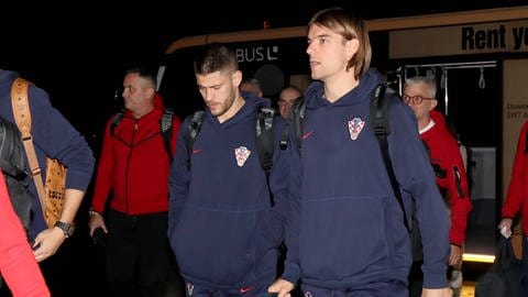 Andrej Kramarić und Borna Sosa in Klamotten der kroatischen Nationalmannschaft steigen mit Gepäck aus einem Flughafen-Bus aus (Foto: IMAGO, Pixsell)