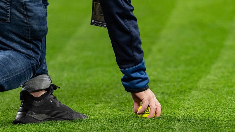 Ein Ordner entfernt einen Tennisball vom Fußballplatz des Dortmunder Stadions.