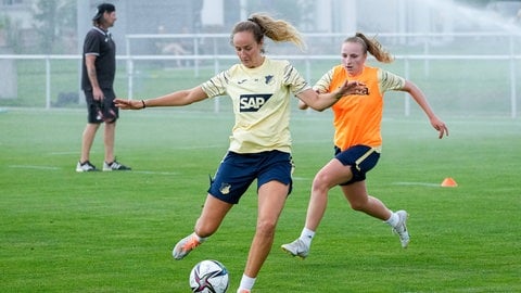 Fabienne Dongus (vorne im hell-gelben Trainingstrikot der TSG Hoffenheim) holt mit dem rechten Fuß zum Torschuss aus. Vanessa Diehm (von rechts kommend im organgen Trainingsleibchen) versucht sie am Torschuss zu hindern. (Foto: IMAGO, IMAGO/Oliver Zimmermann)