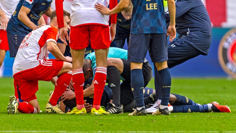 Josuha Guilavogui (FSV Mainz) liegt benommen und verletzt am Boden nach einem Zusammenprall, Schiedsrichter Patrick Ittrich erkennt den lebensgefährlichen Notfall und zieht ihm die verschluckte Zunge heraus, rettet ihm damit seine Gesundheit. 