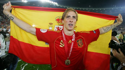 Fernando Torres trägt ein rotes Trikot und hat hält die spanische Flagge hoch. (Foto: IMAGO, Photo by Back Page)