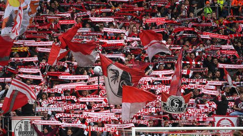 Fans des SC Freiburg im Europa-League-Stadion schwenken Fahnen und Schals. (Foto: IMAGO, IMAGO/Beautiful Sports)