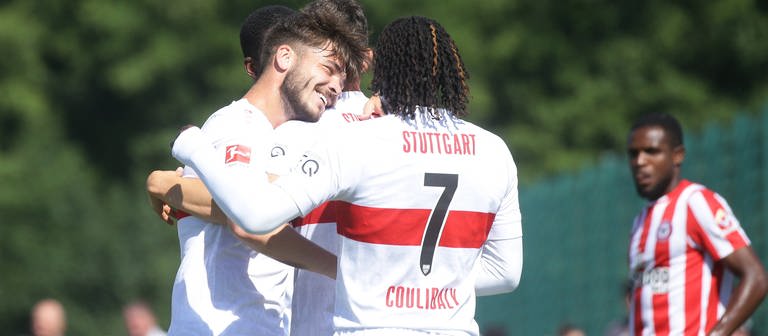  Lilian Egloff und Tanguy Coulibaly und Thomas Kastanaras liegen sich im Arm. Sie feiern Kastanaras' Treffer beim 2:2-Testspiel-Sieg gegen den FC Brentfort in Friedrichshafen. (Foto: IMAGO, IMAGO / Pressefoto Baumann)