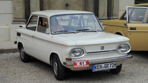 Ein grauer Oldtimer Modell "NSU Prinz" der NSU Motorenwerke steht auf einem Kies-Parkplatz.