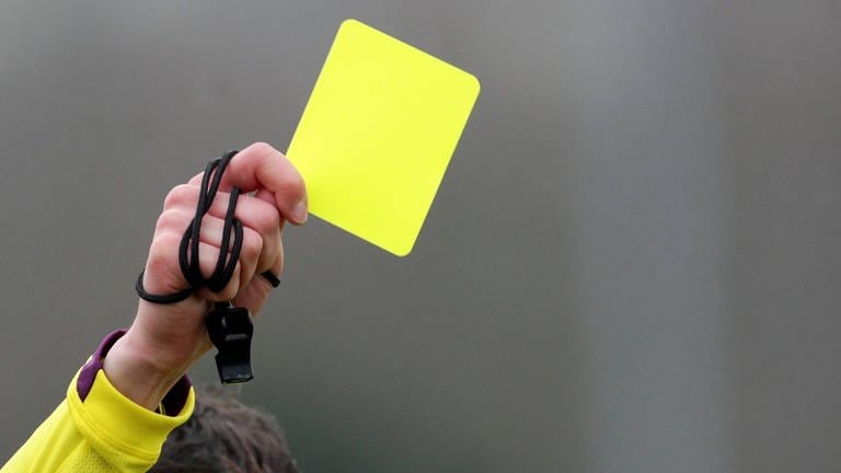 Ein Schiedsrichter zeigt die Gelbe Karte.