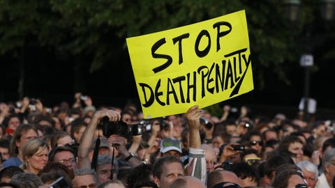 Während einer Rede von Barack Obama in Berlin hält ein Zuhörer ein Plakat hoch und fordert ein Ende der Todesstrafe in den USA (Foto: IMAGO, Metodi Popow)