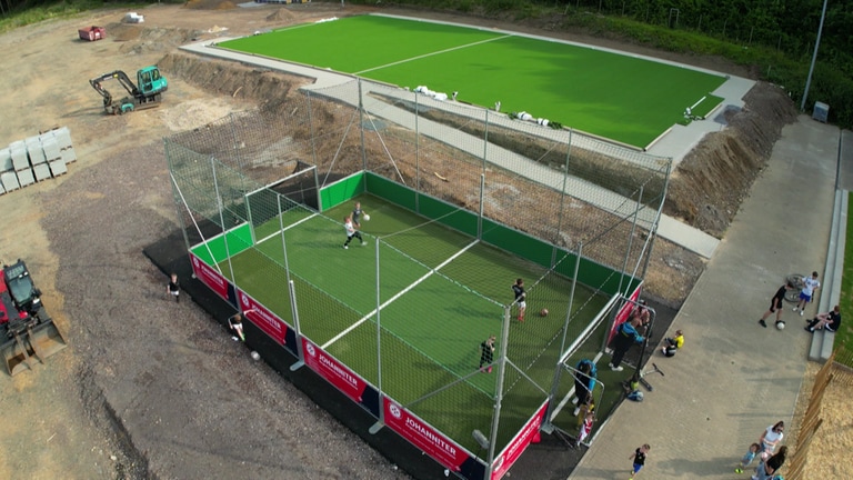 Kinder der Bambini-Mannschaft des SV Dernau trainieren im mobilen Käfig. Im Hintergrund: Das neue Kleinspielfeld. 
