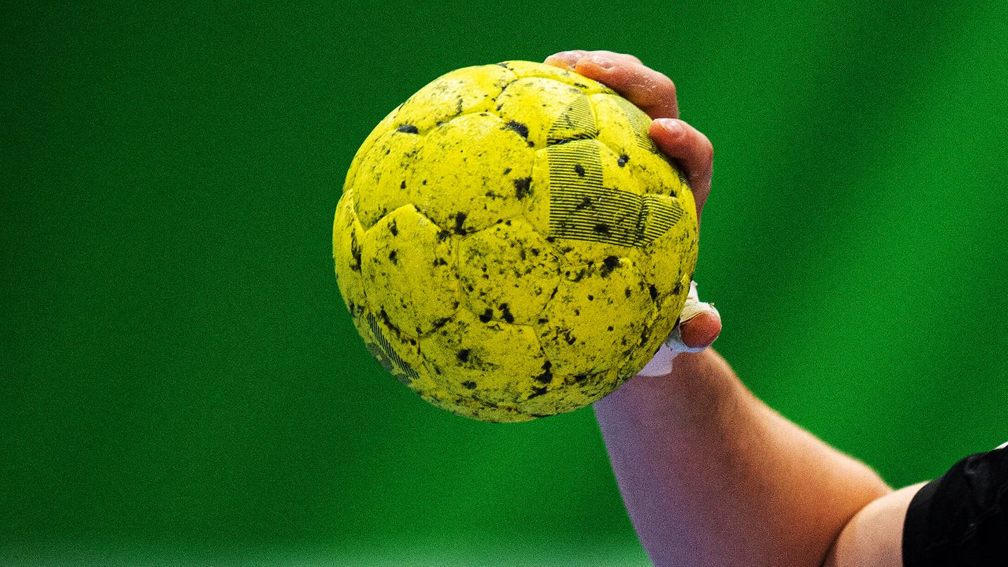 Hand hält verharzten gelben Handball beim Ausholen zum Wurf