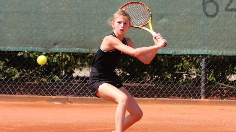 Lilly Greinert hat einen konzentrierten Blick und visiert mit dem Tennisschläger in der Hand den Tennisball an.