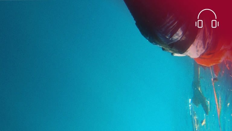 Standbild aus dem Dokumentarfilm Das Purpurmeer: Mensch wird im Mittelmeer über die Wasseroberfläche geschleudert, rotes Overlay mit Icon Kopfhörer (Foto: SWR, pong film, Amel Alzakout)