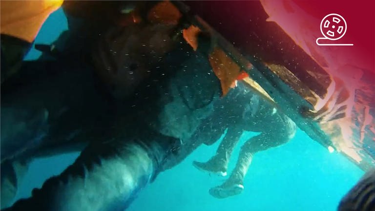 Standbild aus dem Dokumentarfilm Das Purpurmeer: Unterwasseraufnahme von im Mittelmeer treibenden Menschen, rotes Overlay mit Icon Filmstreifen (Foto: SWR, pong film, Amel Alzakout)
