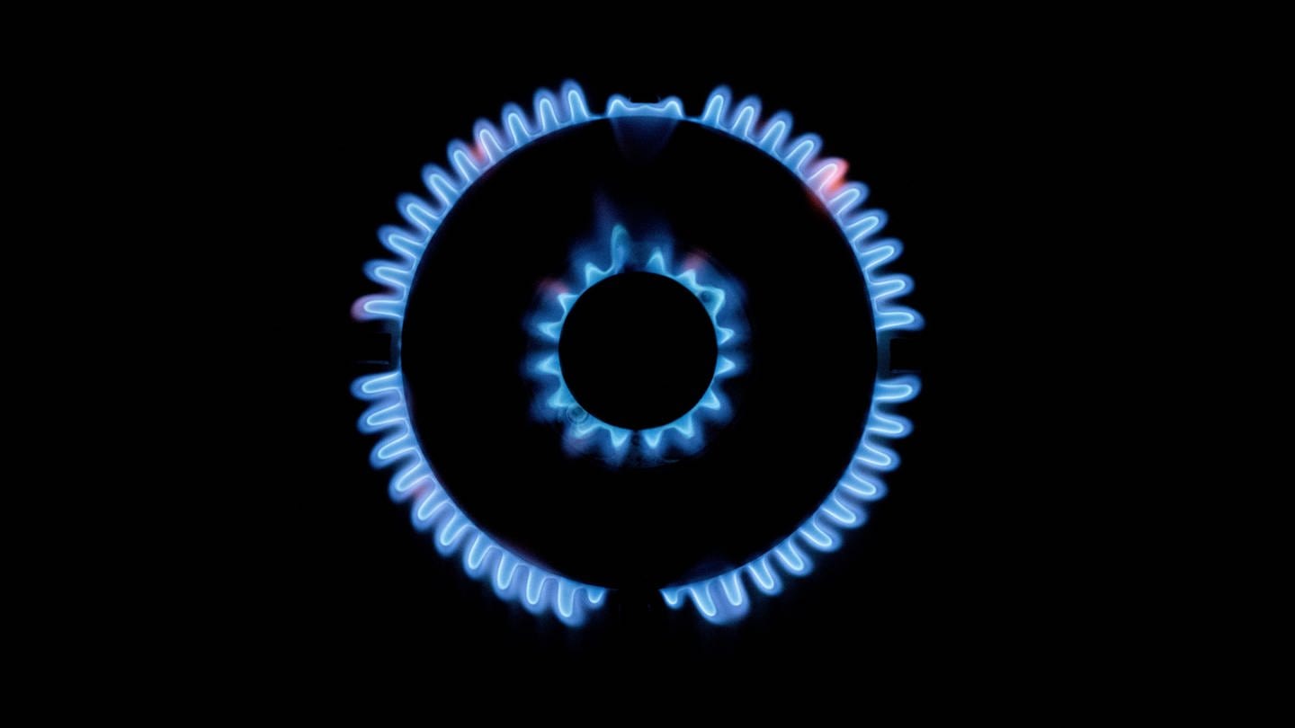 Zahlreiche blau-schimmernde Gas-Flämmchen sind an einem Gasherd zu sehen.
