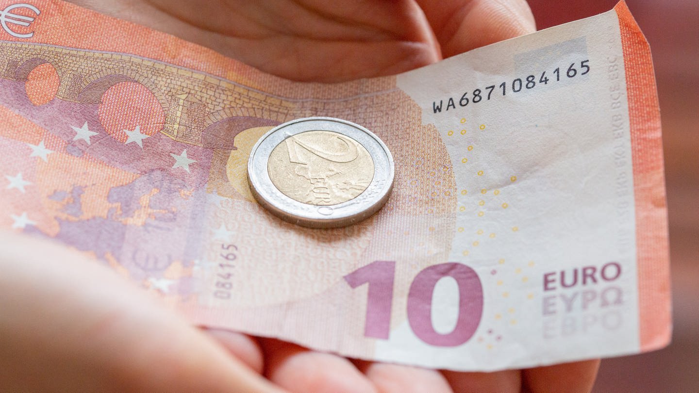Eine Person hält 12 Euro in der Hand. Der gesetzliche Mindestlohn steigt zum 1. Oktober auf 12 Euro je Stunde von zuvor 10,45 Euro.
