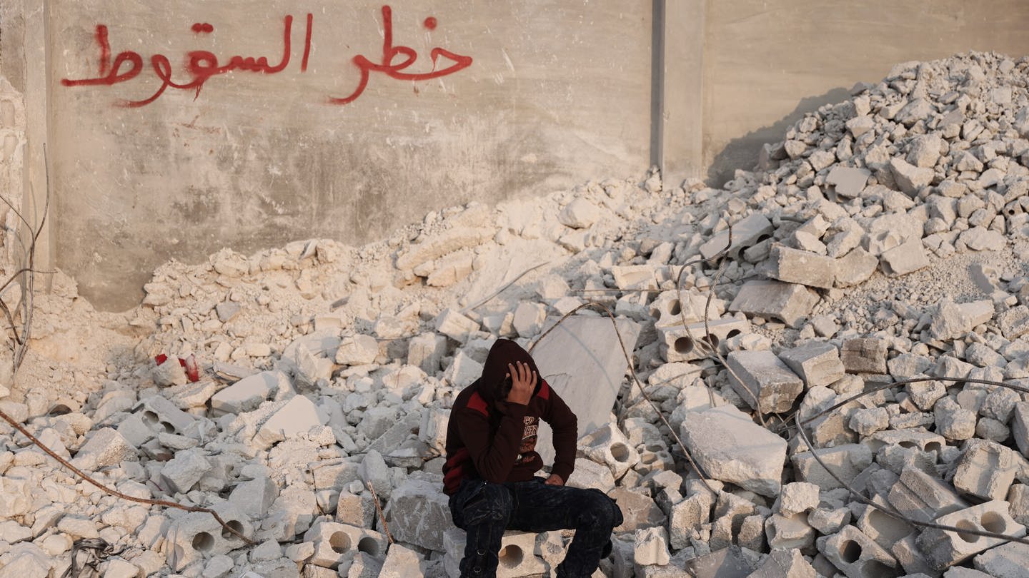 Der 15-jährige Muhammad Al-Mula sitzt in der Nähe seines zerstörten Hauses, das durch das Erdbeben an der türkisch-syrischen Grenze zerstört wurde. Al-Mula wurde gerettet, nachdem er fast zehn Stunden lang unter den Trümmern des Gebäudes eingeschlossen war, in dem er mit seinen fünf Familienmitgliedern gelebt hatte. (Foto: picture-alliance / Reportdienste, Medien_Nr. 396472309)