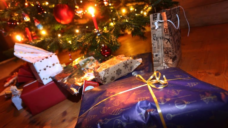 Verpackte Geschenke liegen in einem Wohnzimmer unter einem festlich geschmücktem Weihnachtsbaum. (Foto: picture-alliance / Reportdienste, Picture Alliance)
