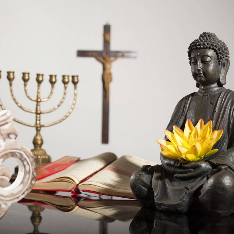 Symbole der Weltreligionen: OM-Symbol für Hinduismus, Menora (siebenarmiger Leuchter) für das Judentum, Kreuz für das Christentum, Koran für den Islam und Buddhafigur für Buddhismus (Foto: IMAGO, IMAGO Bildnummer: 0059755115)