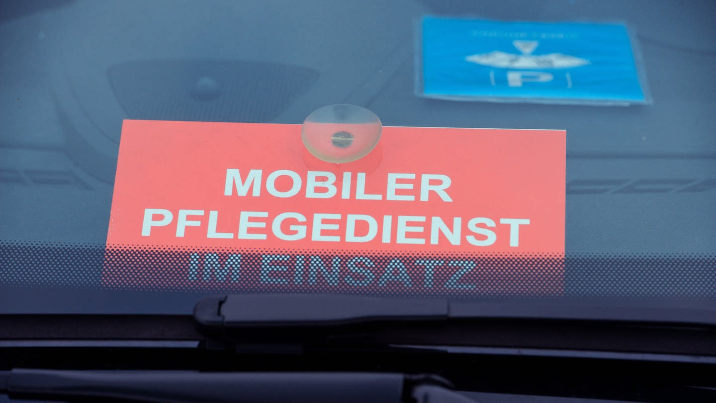 Ein Schild mit dem Schriftzug «Mobiler Pflegedienst im Einsatz» liegt in einem Auto (Foto: picture-alliance / Reportdienste, dpa Bildfunk, picture alliance/dpa/dpa-Zentralbild | Stefan Sauer)
