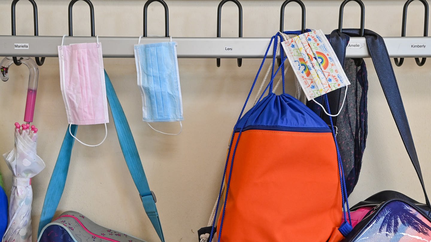 Masken hängen zusammen mit Taschen und Rucksäcken an Kleiderhaken in einem Klassenraum einer Grundschule. (Foto: picture-alliance / Reportdienste, Picture Alliance)