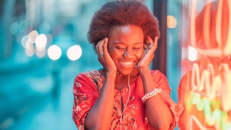 Eine junge Frau hört Musik und lacht (Foto: IMAGO, Javier De La Torre Sebastian )