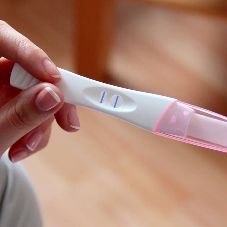 Eine Frau hält einen Schwangerschaftstest in der Hand. (Foto: dpa Bildfunk, Picture Alliance)