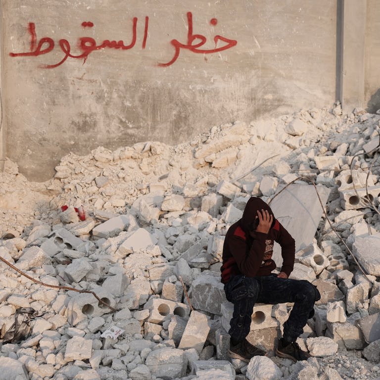 Der 15-jährige Muhammad Al-Mula sitzt in der Nähe seines zerstörten Hauses, das durch das Erdbeben an der türkisch-syrischen Grenze zerstört wurde. Al-Mula wurde gerettet, nachdem er fast zehn Stunden lang unter den Trümmern des Gebäudes eingeschlossen war, in dem er mit seinen fünf Familienmitgliedern gelebt hatte. (Foto: picture-alliance / Reportdienste, Medien_Nr. 396472309)