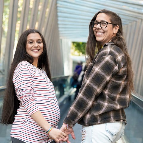 Ein lesbisches schwangeres Paar, das sich an den Händen hält