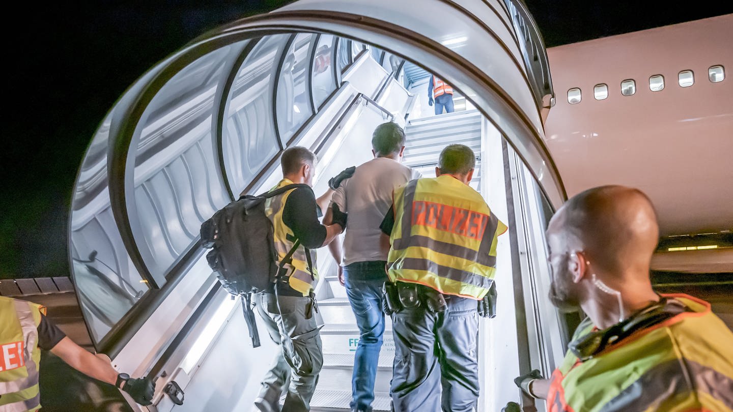 Polizeibeamte begleiten im Sommer 2019 einen Afghanen auf dem Flughafen Leipzig-Halle in ein Charterflugzeug (Foto: dpa Bildfunk, picture alliance/dpa | Michael Kappeler)