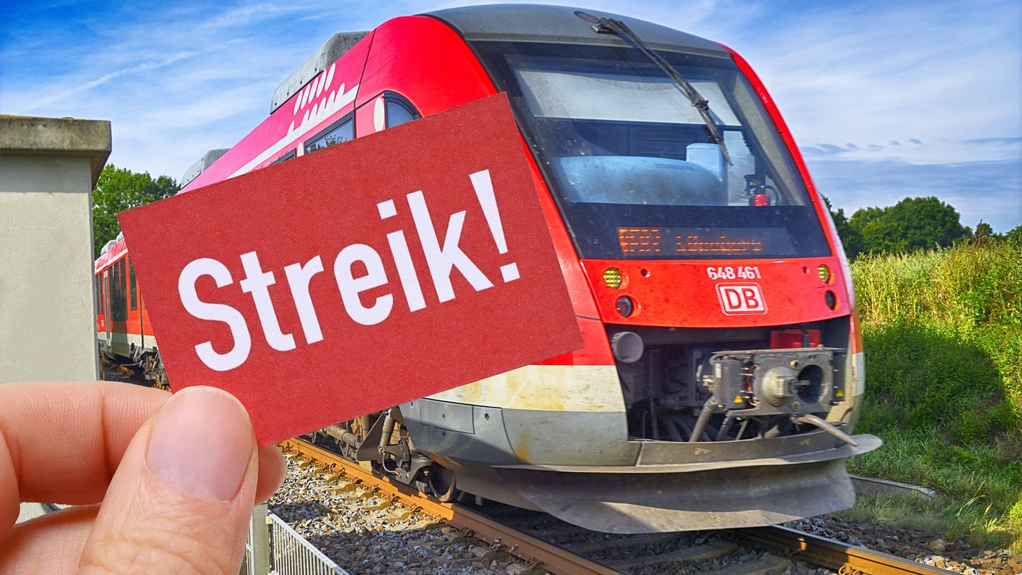 Hand hält Schild mit Aufschrift Streik vor einer Bahn (Foto: IMAGO, Christian Ohde)