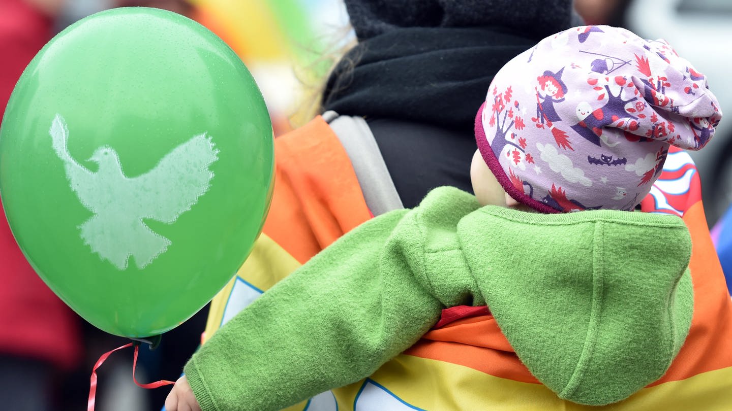 Ein kleines Kind hält während eines Ostermarsches einen Luftballon mit einer Friedenstaube fest. (Foto: picture-alliance / Reportdienste, Picture Alliance)