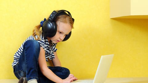 Mädchen sitzt mit Kopfhörern vor einem Laptop. (Foto: Thinkstock)