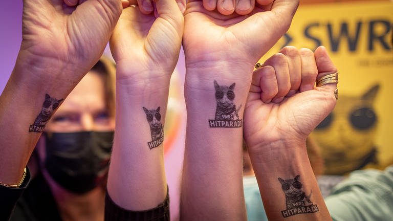 Vier Menschen halten ihre Handgelenke mit einem SWR1 Hitparaden-Tattoo in die Kamera (Foto: SWR)