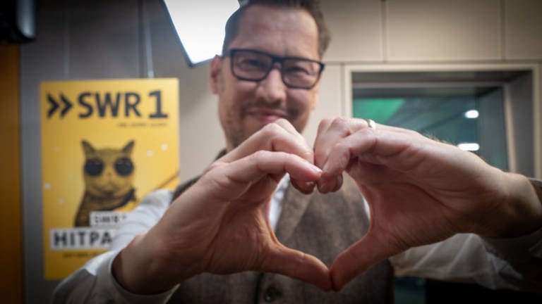 SWR1 Moderator Jochen Stöckle zeigt mit seinen Händen ein Herz