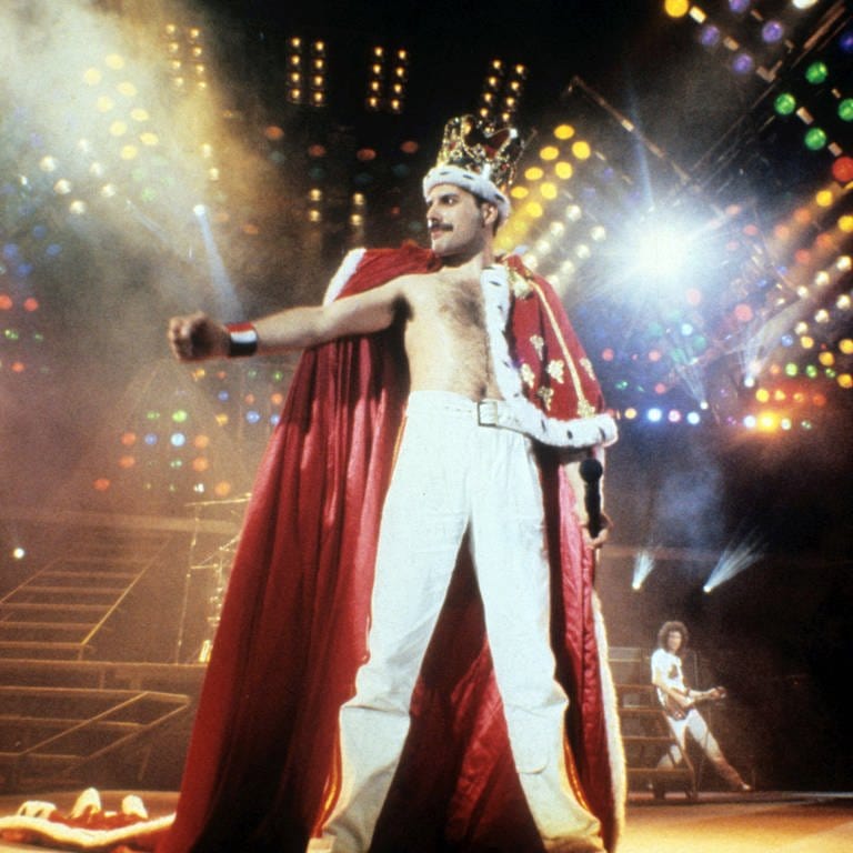 Freddie Mercury steht bei seinem Konzert in Mannheim 1986 auf der Bühne und trägt eine Krone und einen königlichen Umhang