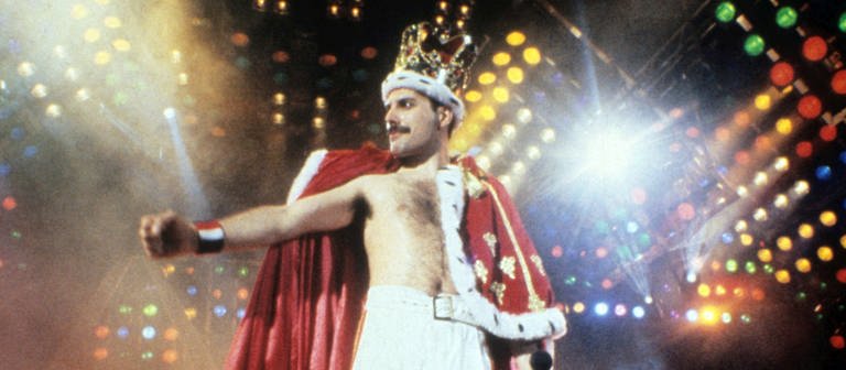 Freddie Mercury steht bei seinem Konzert in Mannheim 1986 auf der Bühne und trägt eine Krone und einen königlichen Umhang (Foto: picture-alliance / Reportdienste, Photoshot)