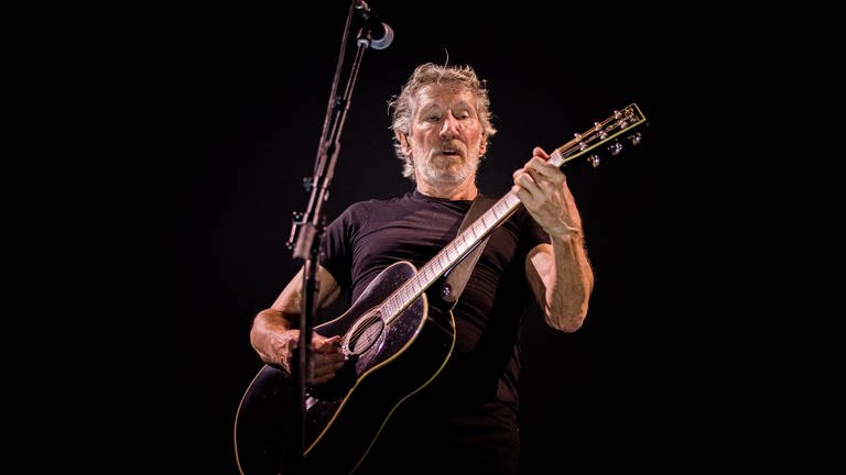 Pink Floyd Sänger Roger Waters steht auf einer Bühne und spielt Gitarre. (Foto: dpa Bildfunk, Picture Alliance)