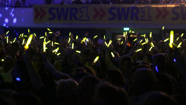 Publikum mit gelben Leuchtstäben