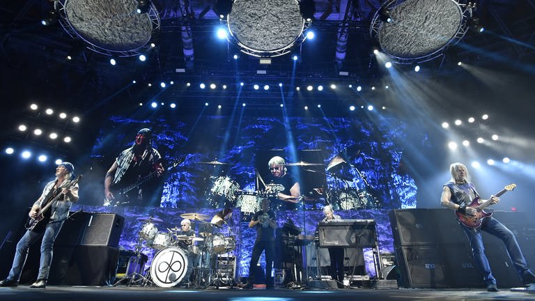 Die Musiker der Band "Deep Purple" stehen in einem blauen Licht auf der Bühne und machen Musik.