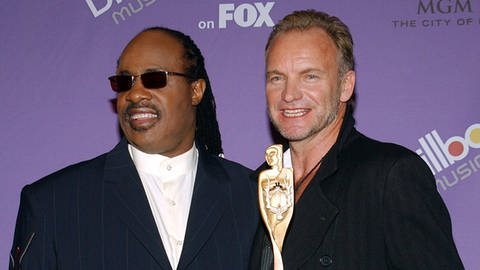 imago images  UPI Photo (Foto: IMAGO, Stevie Wonder steht zusammen mit Sting vor einer Fotowand der Billboard Music Awards.)