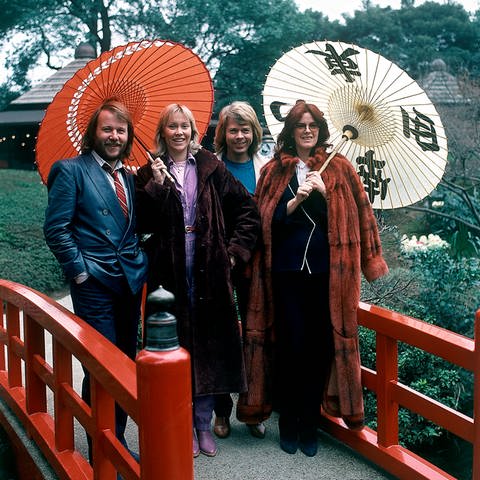 Members of the pop group ABBA try old-style Japanese umbrellas, made of bamboo frame and coarse oil paper, in a light spring rain at their hotel's Japanese garden, March 14, 1980. (Foto: dpa Bildfunk, picture alliance / ASSOCIATED PRESS | Tsugufumi Matsumoto)