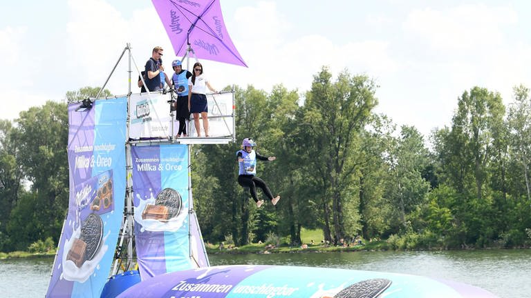 Frau springt von einem Turm auf ein riesiges Luftkissen im Wasser (Foto: picture-alliance / Reportdienste, Helmut Fohringer)