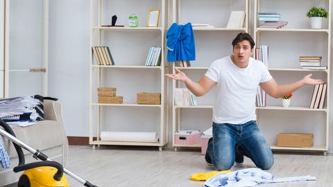 Ein Mann putzt und räumt die Wohnung auf. (Foto: picture-alliance / Reportdienste, Zoonar | Elnur Amikishiyev)